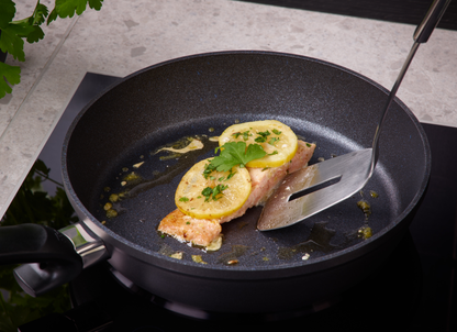 Beschichtete Stielpfanne der Fissler Serie Adamant® beim Fisch braten auf dem Induktionskochfeld 