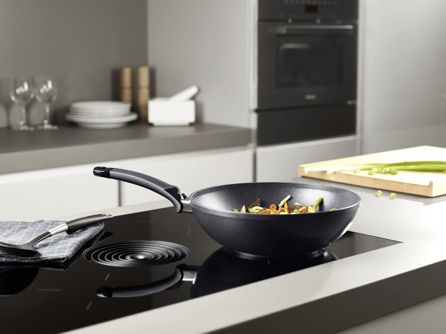 Beschichtete Wokpfanne der Fissler Serie Adamant® auf dem Herd mit asiatischen Gericht