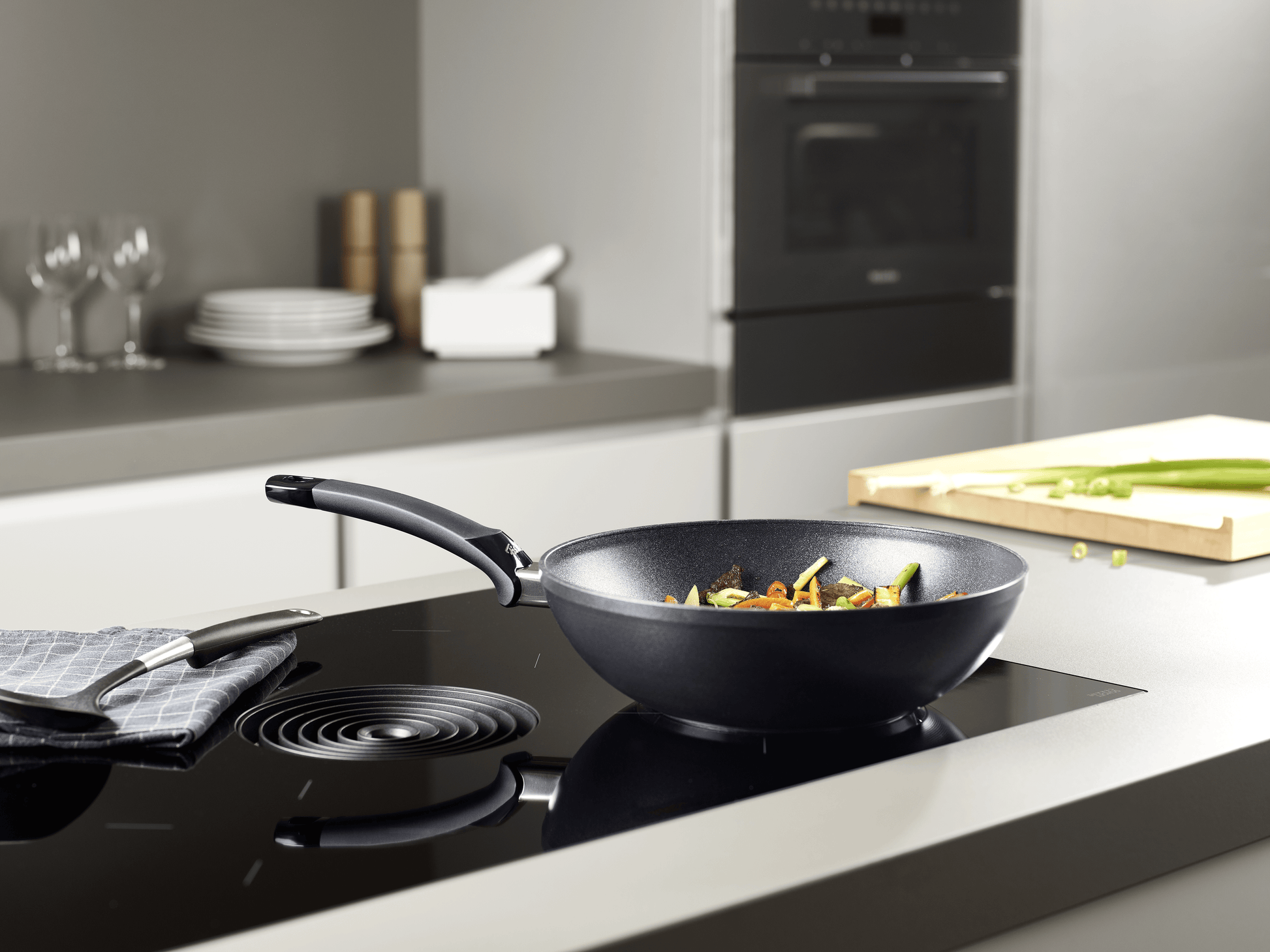 Beschichtete Wokpfanne der Fissler Serie Adamant® auf dem Herd mit asiatischen Gericht