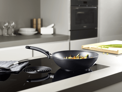Beschichtete Wokpfanne der Fissler Serie Adamant® auf dem Herd mit asiatischen Gericht