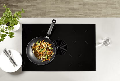 Beschichtete Wokpfanne der Fissler Serie Adamant® auf dem Herd mit asiatischen Gericht
